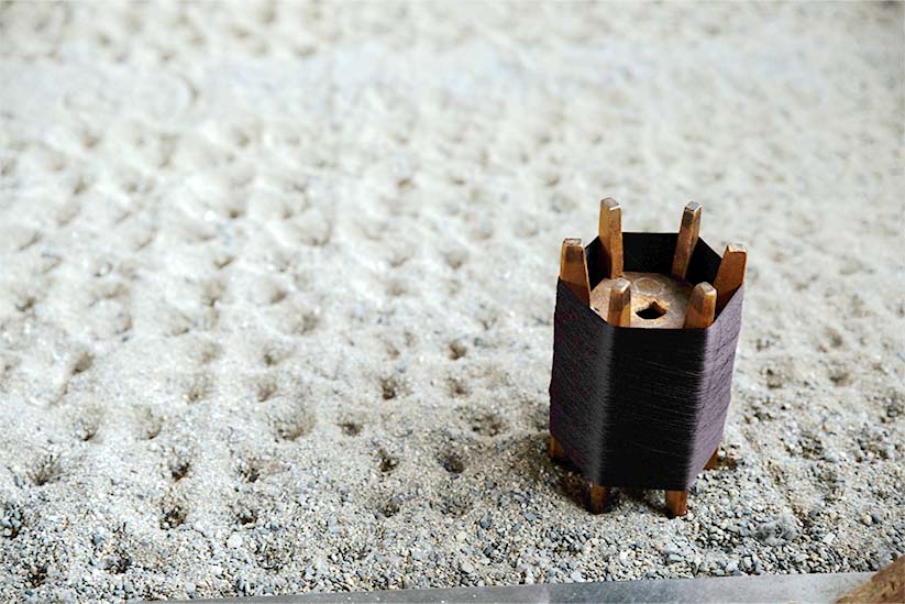 白根澤の工房の風景。砂の上に糸巻きが置かれている