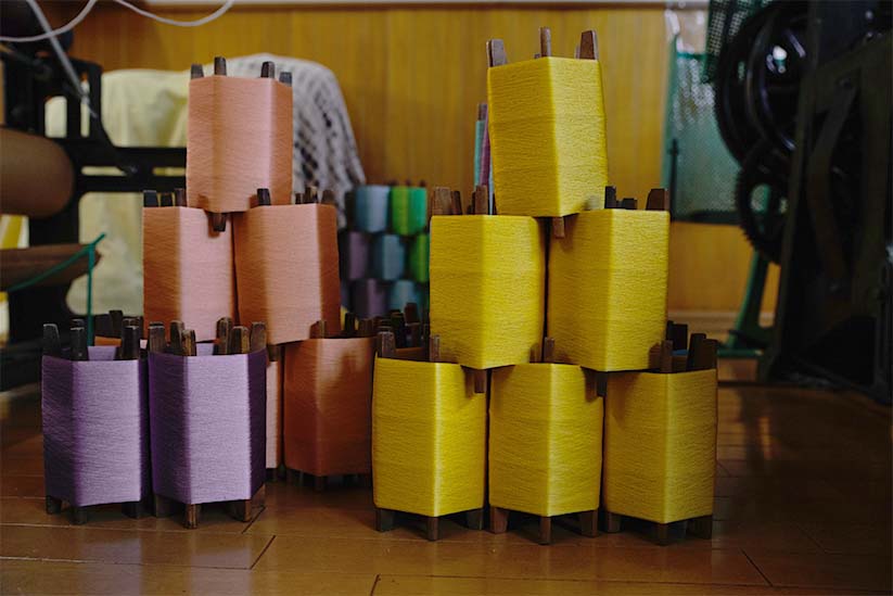 新田工房内に展示された色見本と、紬に使用された染色された糸