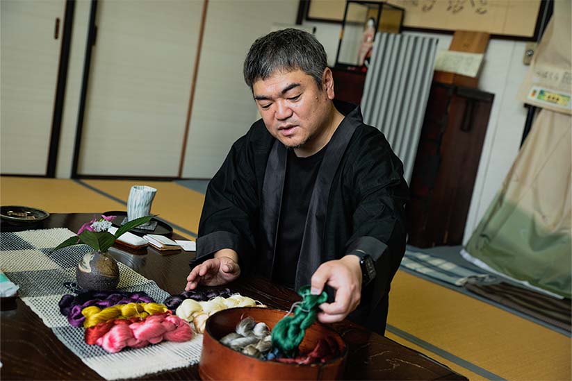 染色された糸を手に、解説をする諏訪豪一さん